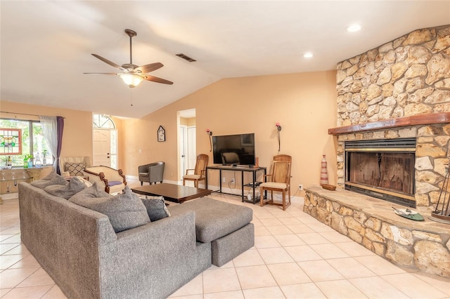 living room with a stone fireplace, ceiling fan, light tile patterned floors, and vaulted ceiling