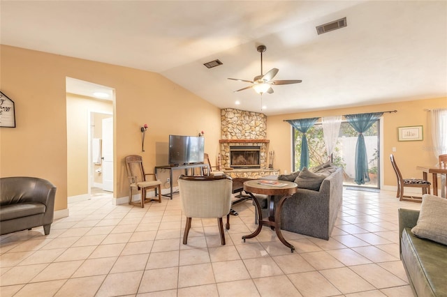 tiled living room with ceiling fan, a stone fireplace, and lofted ceiling