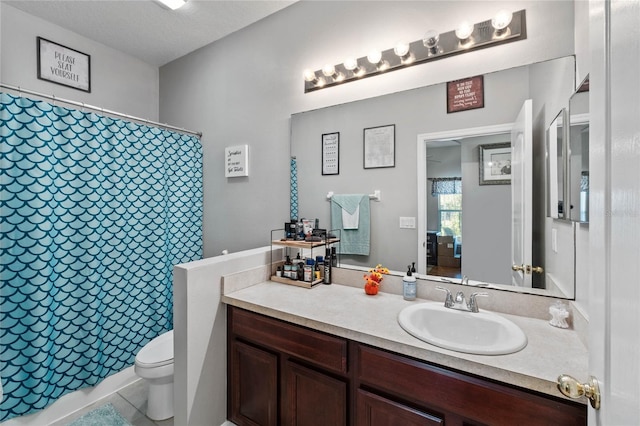 bathroom with tile patterned flooring, a textured ceiling, vanity, and toilet