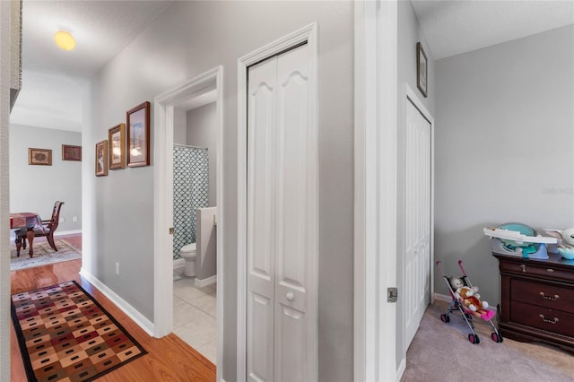 corridor with a textured ceiling and light hardwood / wood-style flooring