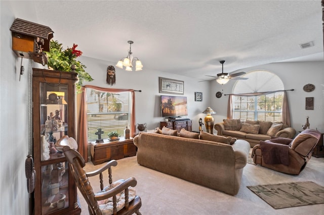 carpeted living room with ceiling fan with notable chandelier and a textured ceiling