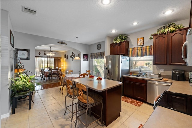 kitchen with ceiling fan, decorative light fixtures, a breakfast bar, a kitchen island, and appliances with stainless steel finishes