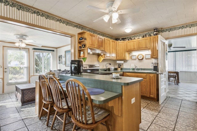 kitchen with stainless steel electric stove, sink, kitchen peninsula, crown molding, and a breakfast bar area