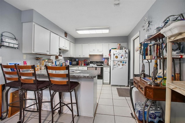 kitchen featuring white cabinetry, a breakfast bar, white fridge, and electric range oven