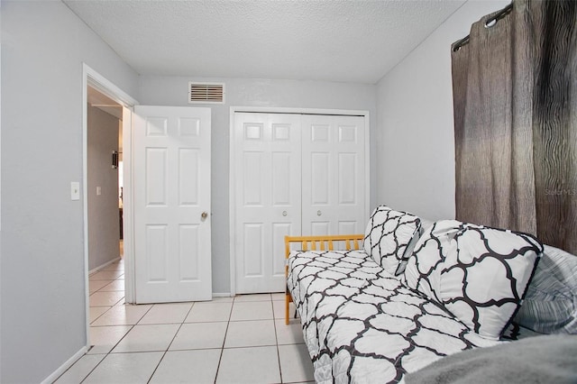 tiled bedroom featuring a closet and a textured ceiling