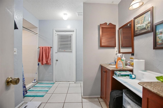 bathroom featuring tile patterned flooring, vanity, a textured ceiling, and walk in shower