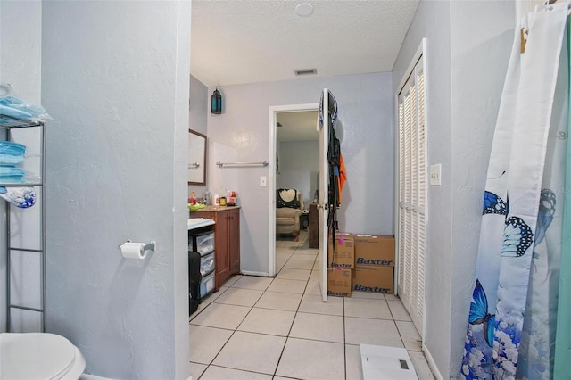 bathroom with tile patterned flooring, vanity, toilet, and a textured ceiling