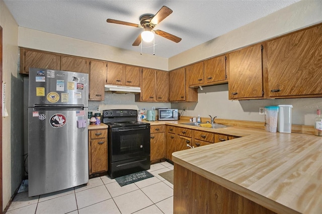 kitchen featuring a textured ceiling, sink, black electric range, stainless steel refrigerator, and light tile patterned flooring