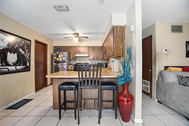 1571 S Boundary St, Deland, FL 32720 - kitchen featuring freestanding refrigerator, stove, a peninsula, under cabinet range hood, and a ceiling fan