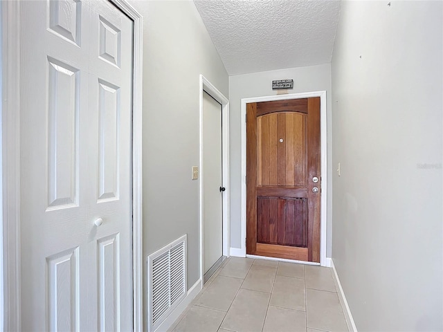 doorway to outside with light tile patterned floors and a textured ceiling