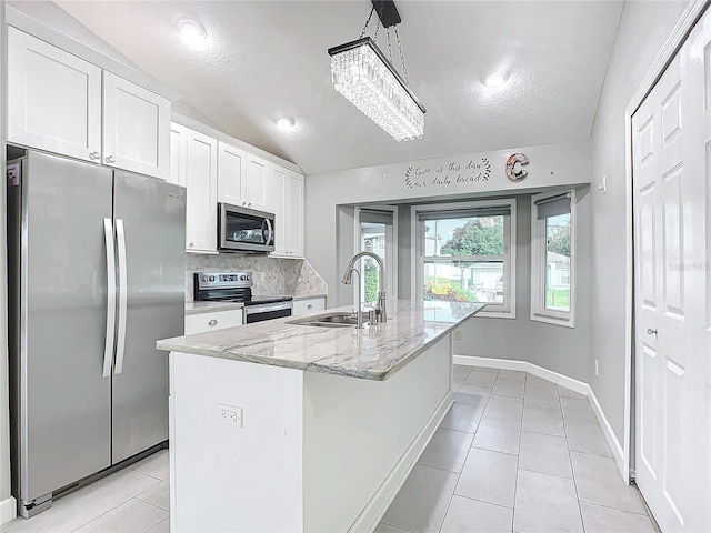 kitchen with white cabinetry, sink, stainless steel appliances, a notable chandelier, and a kitchen island with sink