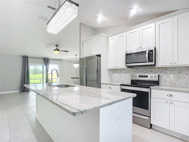 kitchen with backsplash, stainless steel appliances, sink, a center island with sink, and white cabinets