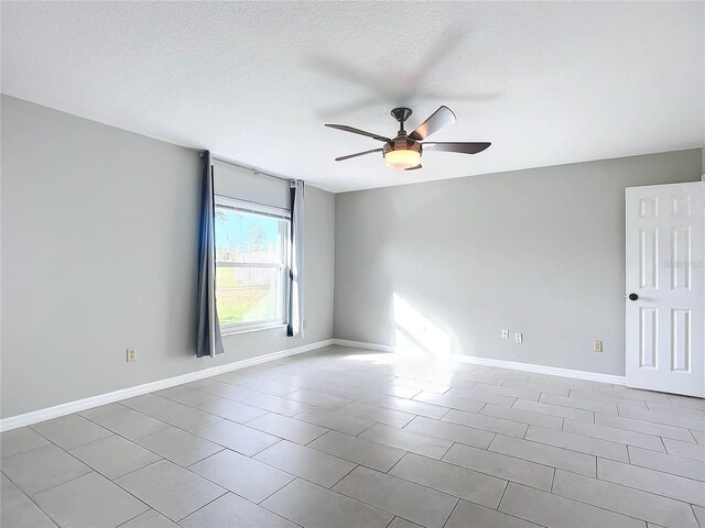 spare room with ceiling fan, light tile patterned floors, and a textured ceiling