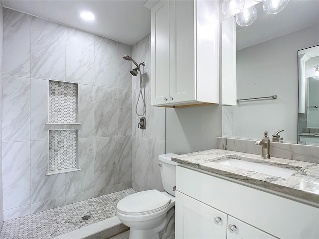 bathroom with tiled shower, vanity, and toilet