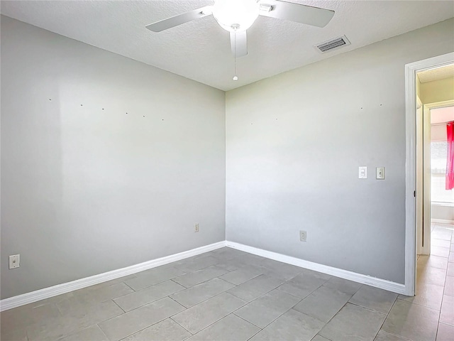 unfurnished room featuring ceiling fan, light tile patterned floors, and a textured ceiling