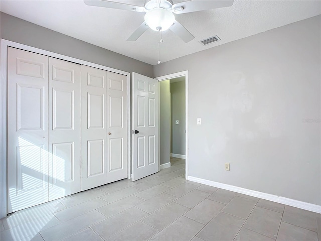 unfurnished bedroom featuring ceiling fan, a closet, light tile patterned floors, and a textured ceiling