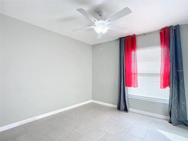 empty room featuring ceiling fan, light tile patterned flooring, and a textured ceiling