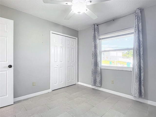 unfurnished bedroom featuring ceiling fan, a closet, light tile patterned floors, and a textured ceiling