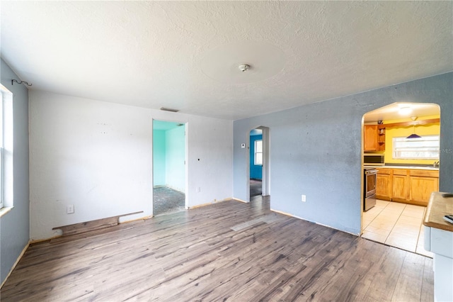 unfurnished living room featuring sink, light hardwood / wood-style flooring, and a textured ceiling