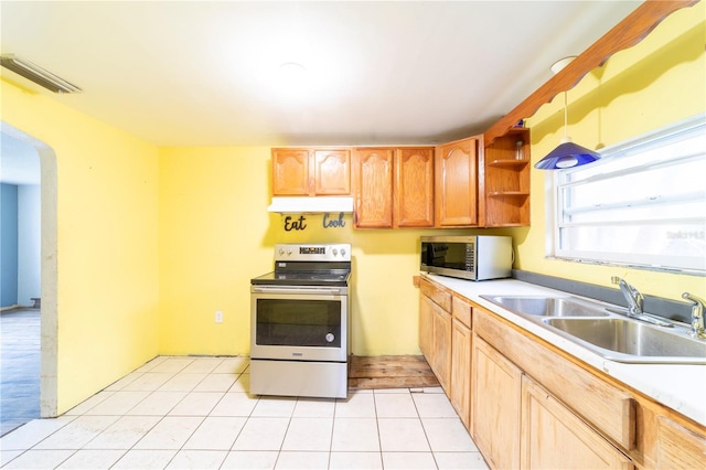 kitchen with appliances with stainless steel finishes, sink, light tile patterned floors, and decorative light fixtures