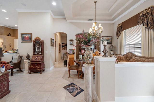 living room with a tray ceiling, light tile patterned flooring, ornamental molding, and a notable chandelier