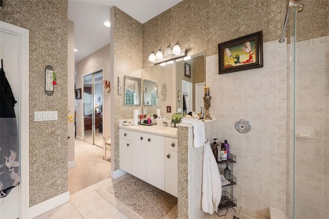 bathroom featuring tile patterned flooring, a tile shower, and vanity