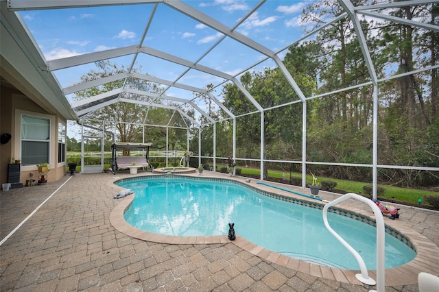 view of swimming pool with glass enclosure, a patio area, and a jacuzzi