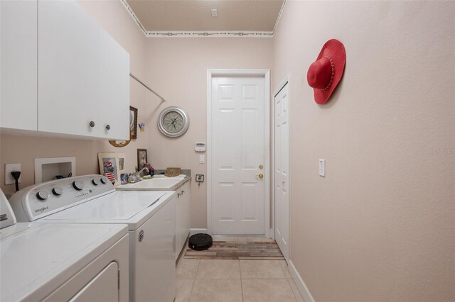 washroom featuring washer and clothes dryer, cabinets, light tile patterned floors, and sink