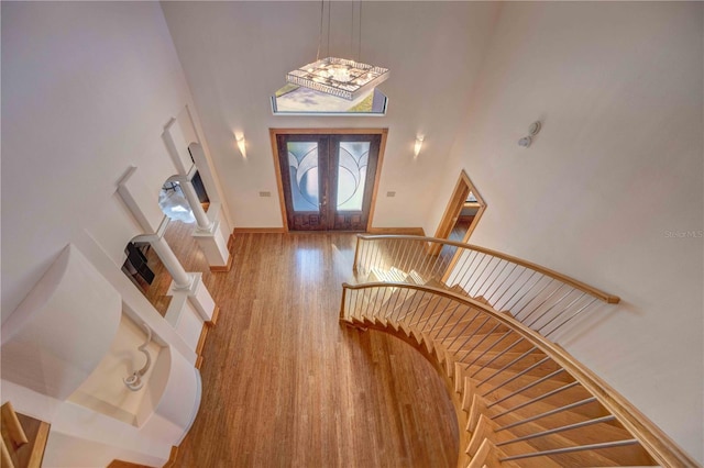 entrance foyer featuring hardwood / wood-style floors, a towering ceiling, and french doors