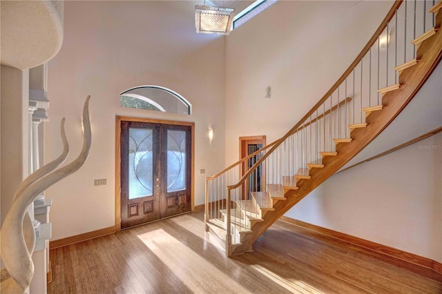 entryway featuring light hardwood / wood-style floors, a towering ceiling, and french doors