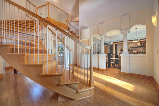 stairway featuring wood-type flooring and an inviting chandelier