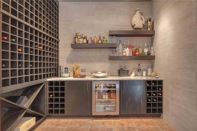 wine cellar featuring light tile patterned floors, beverage cooler, and tile walls