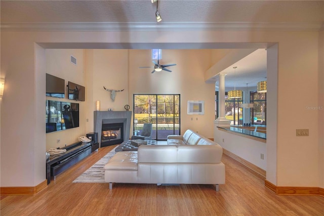 living room featuring ceiling fan, light hardwood / wood-style flooring, crown molding, and a textured ceiling