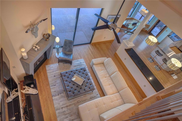 living room featuring a high ceiling, light hardwood / wood-style floors, and decorative columns