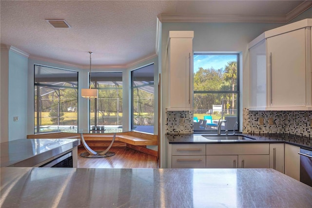 kitchen with white cabinetry, sink, pendant lighting, decorative backsplash, and hardwood / wood-style flooring