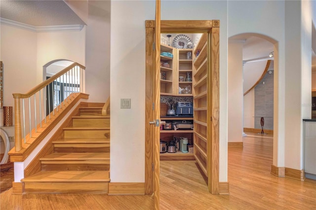 stairway with hardwood / wood-style floors, a textured ceiling, and ornamental molding