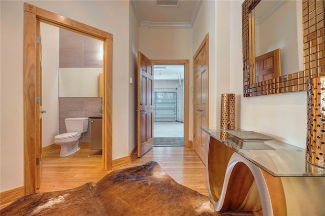 hall with light hardwood / wood-style flooring and ornamental molding