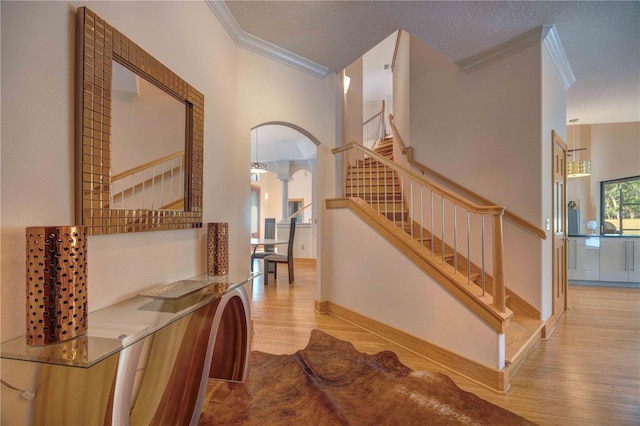 interior space with decorative columns, ornamental molding, a textured ceiling, and hardwood / wood-style flooring