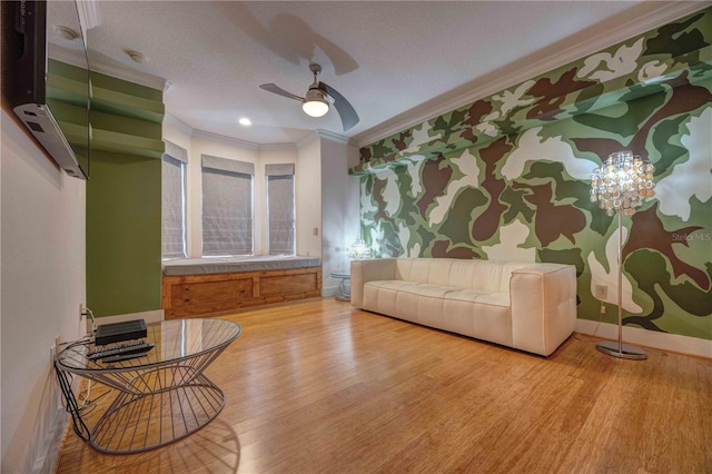 living room featuring wood-type flooring, ceiling fan with notable chandelier, a textured ceiling, and ornamental molding