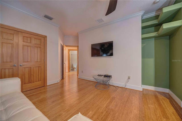 living room featuring crown molding, light hardwood / wood-style flooring, and a textured ceiling