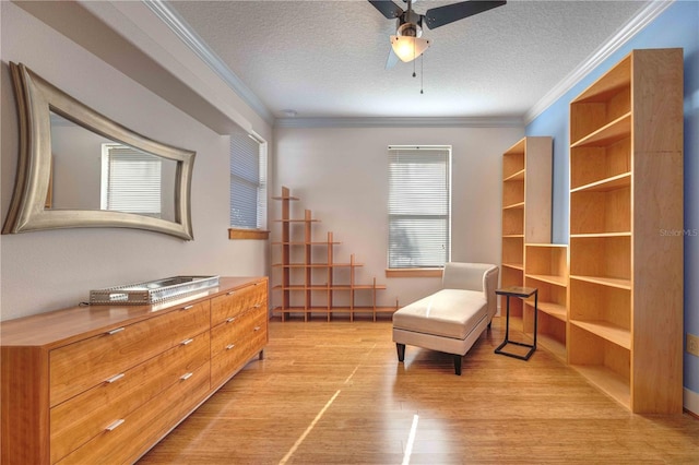 living area with ceiling fan, ornamental molding, a textured ceiling, and light wood-type flooring