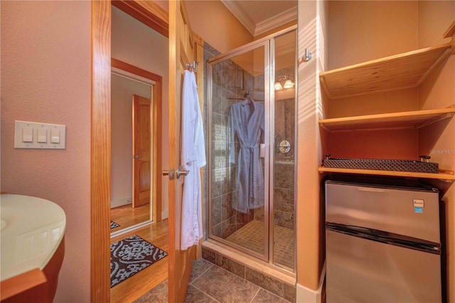 bathroom with tile patterned flooring, a shower with door, and crown molding