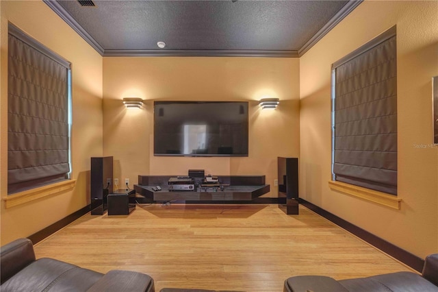 home theater room featuring a textured ceiling, light wood-type flooring, and crown molding