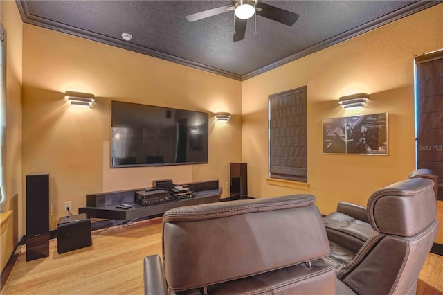 home theater room with a textured ceiling, ceiling fan, light wood-type flooring, and crown molding