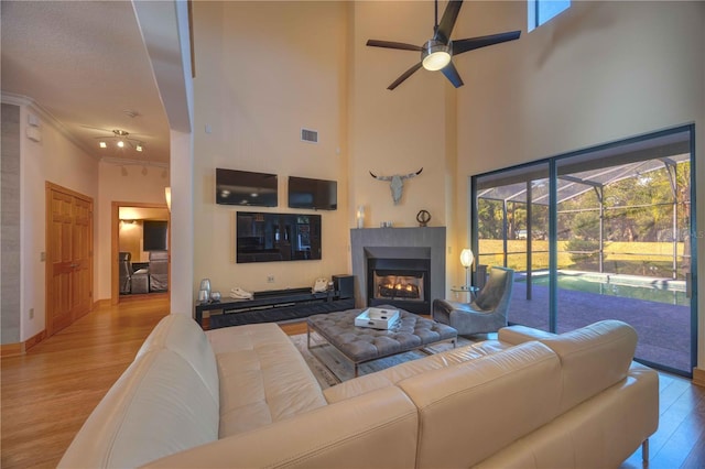 living room featuring a towering ceiling, light hardwood / wood-style flooring, and ornamental molding