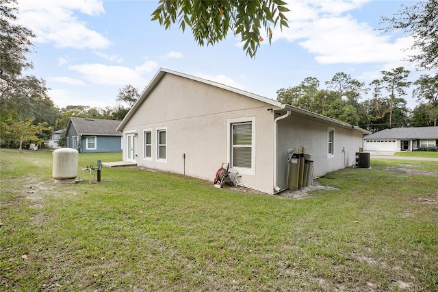 rear view of property featuring central air condition unit and a yard