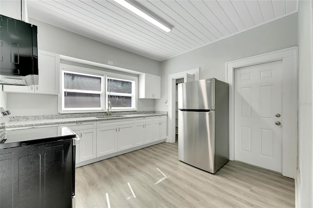 kitchen featuring stainless steel fridge, stove, white cabinets, and light wood-type flooring