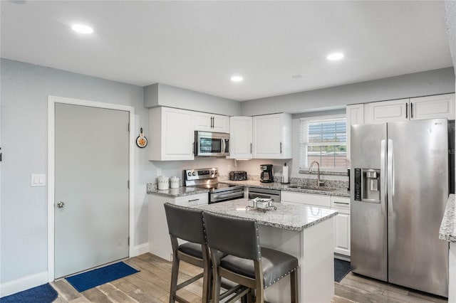 kitchen with a kitchen island, light wood-type flooring, stainless steel appliances, and white cabinetry