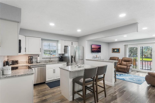 kitchen featuring a breakfast bar, a kitchen island, dark hardwood / wood-style floors, and stainless steel appliances