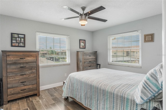 bedroom with wood-type flooring, a textured ceiling, multiple windows, and ceiling fan